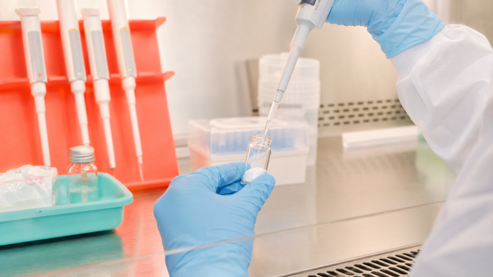 Gloved laboratory researcher adding measured diluent to a lyophilized research vial with a pipette